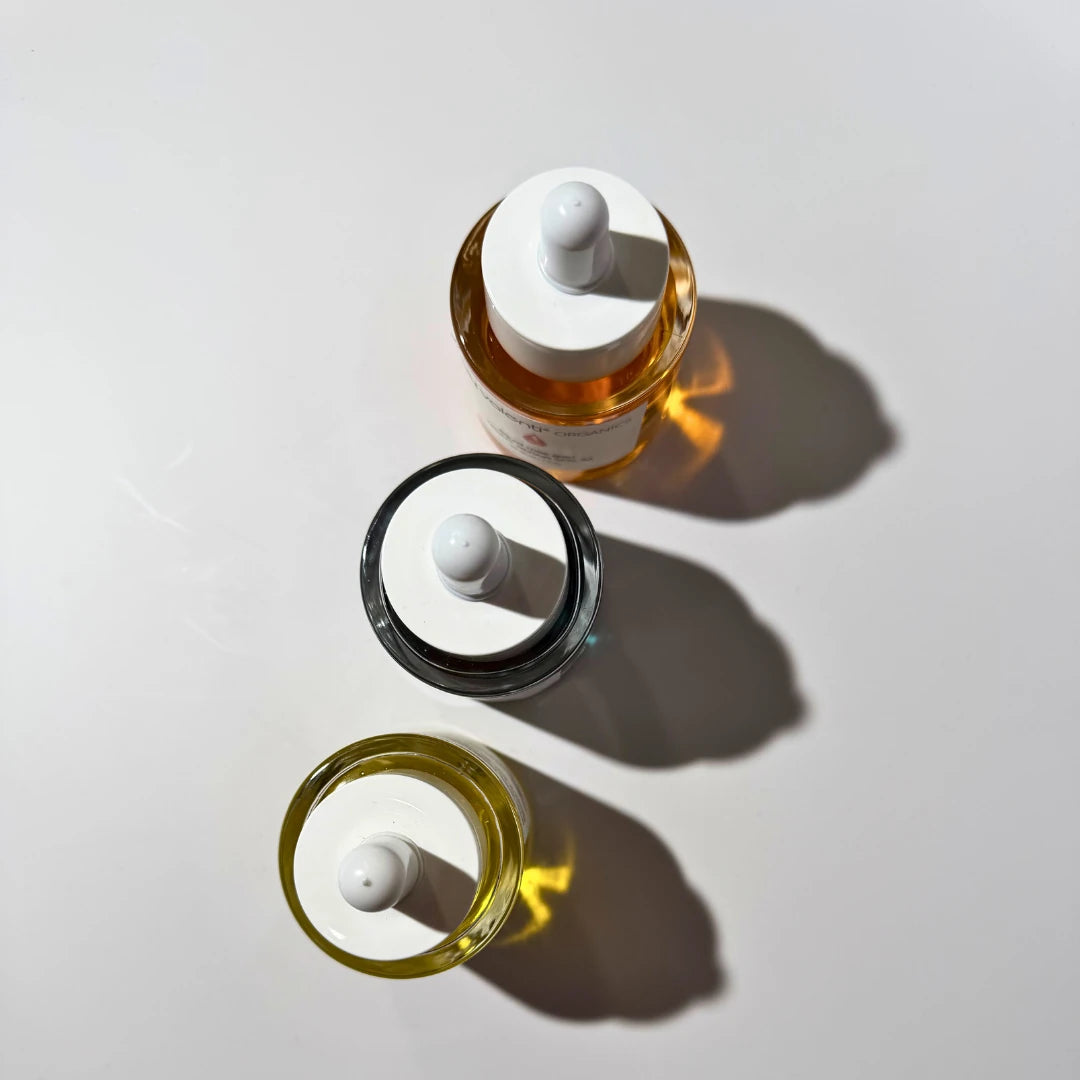 Three by valenti serum glass bottles with white caps on a light gray background