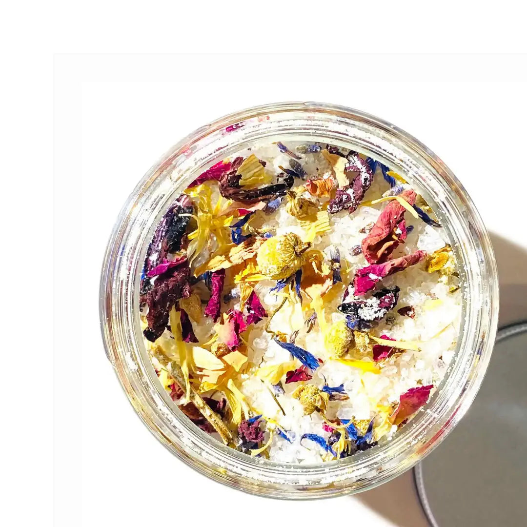 By Valenti jar of milk bath salt with goat's milk and dried wildflower petals on a white background
