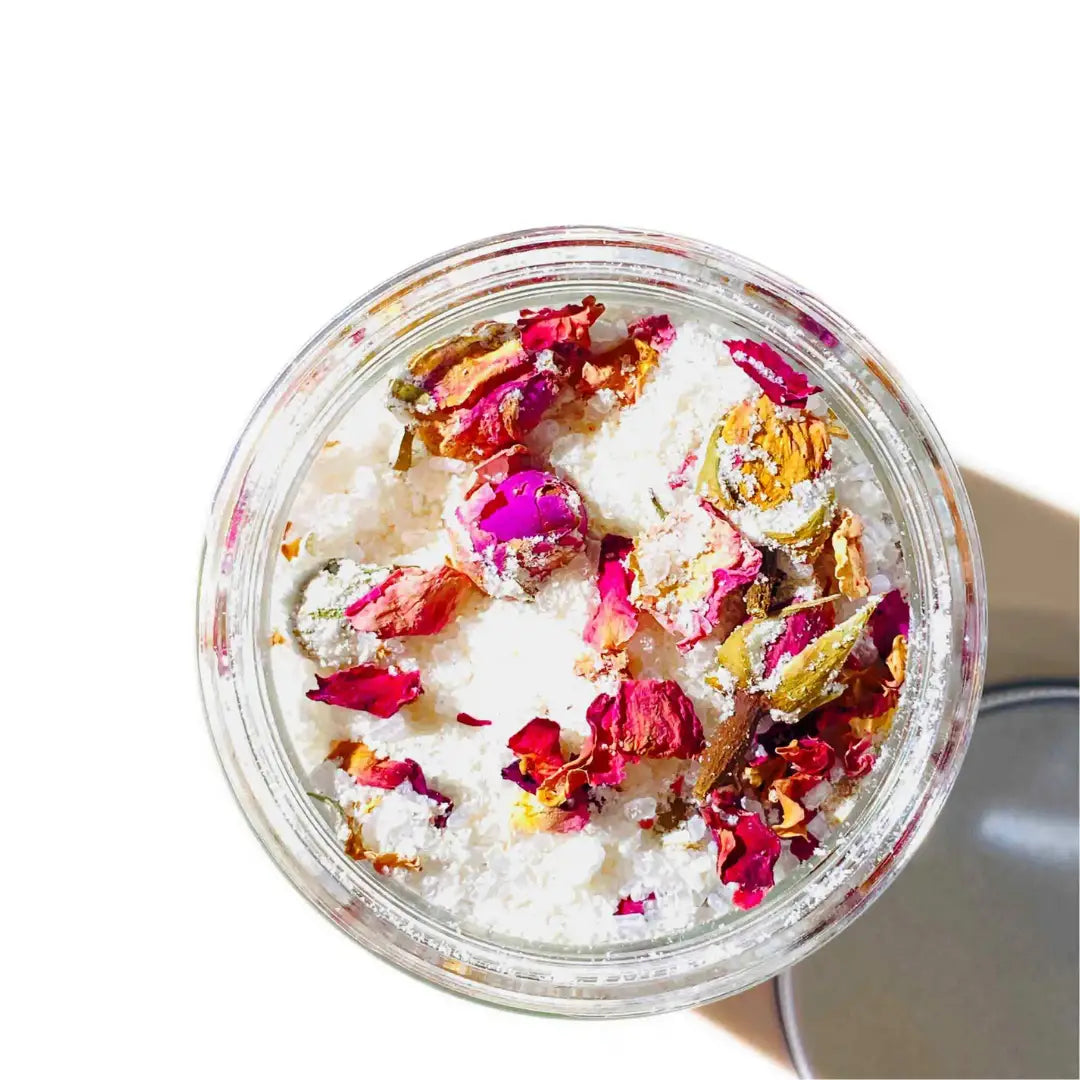 By Valenti Organics jar of bath salts with goat's milk and colorful rose petals and dried flowers on a white background