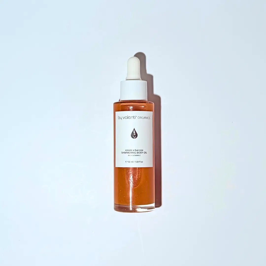 By Valenti shimmering body serum with vitamin c with dropper on a light blue background