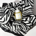 By Valenti skincare bottle of bakuchiol smoothing serum with dropper on a zebra-patterned bandana