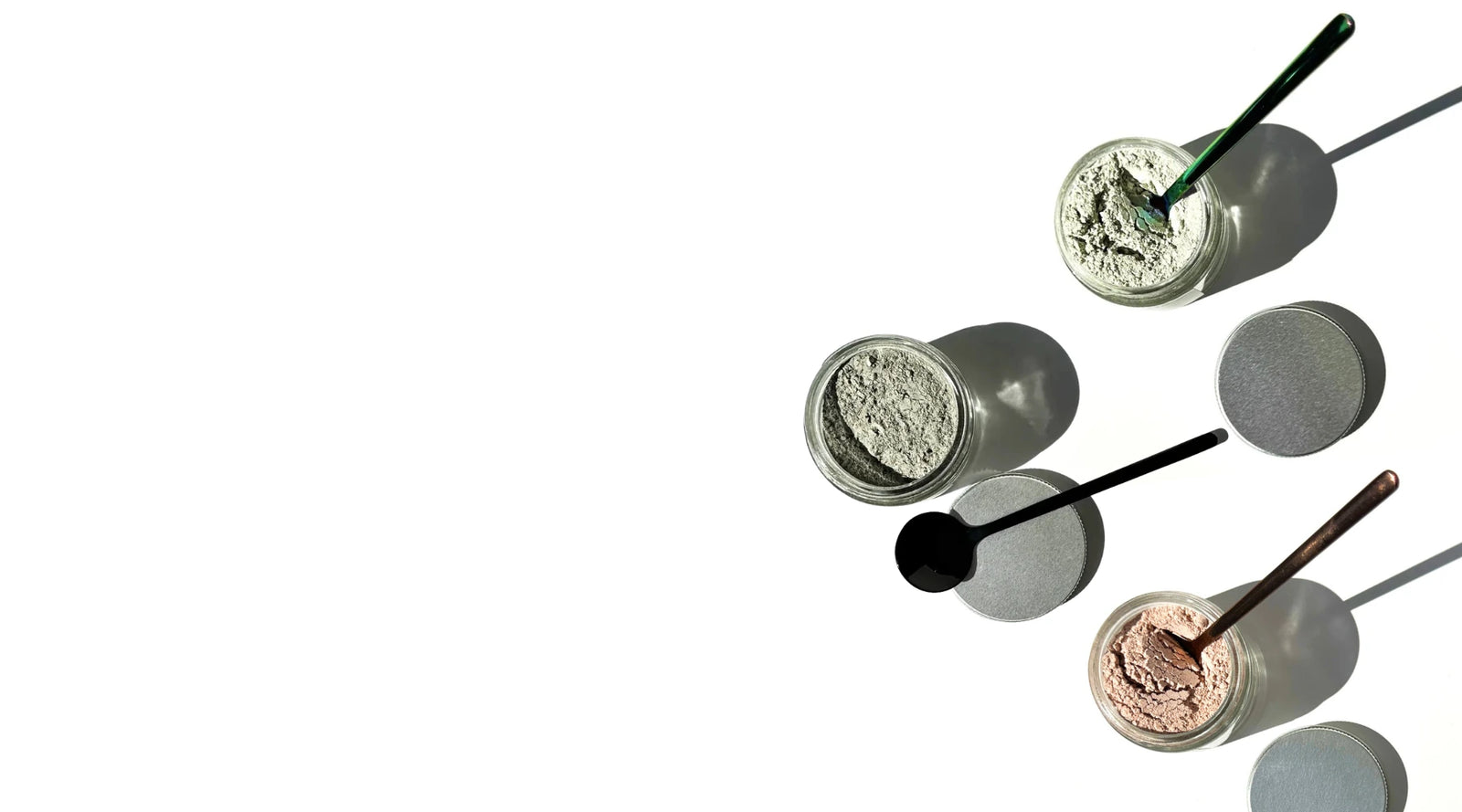 By Valenti cosmetic powders in small containers with applicators on a white background