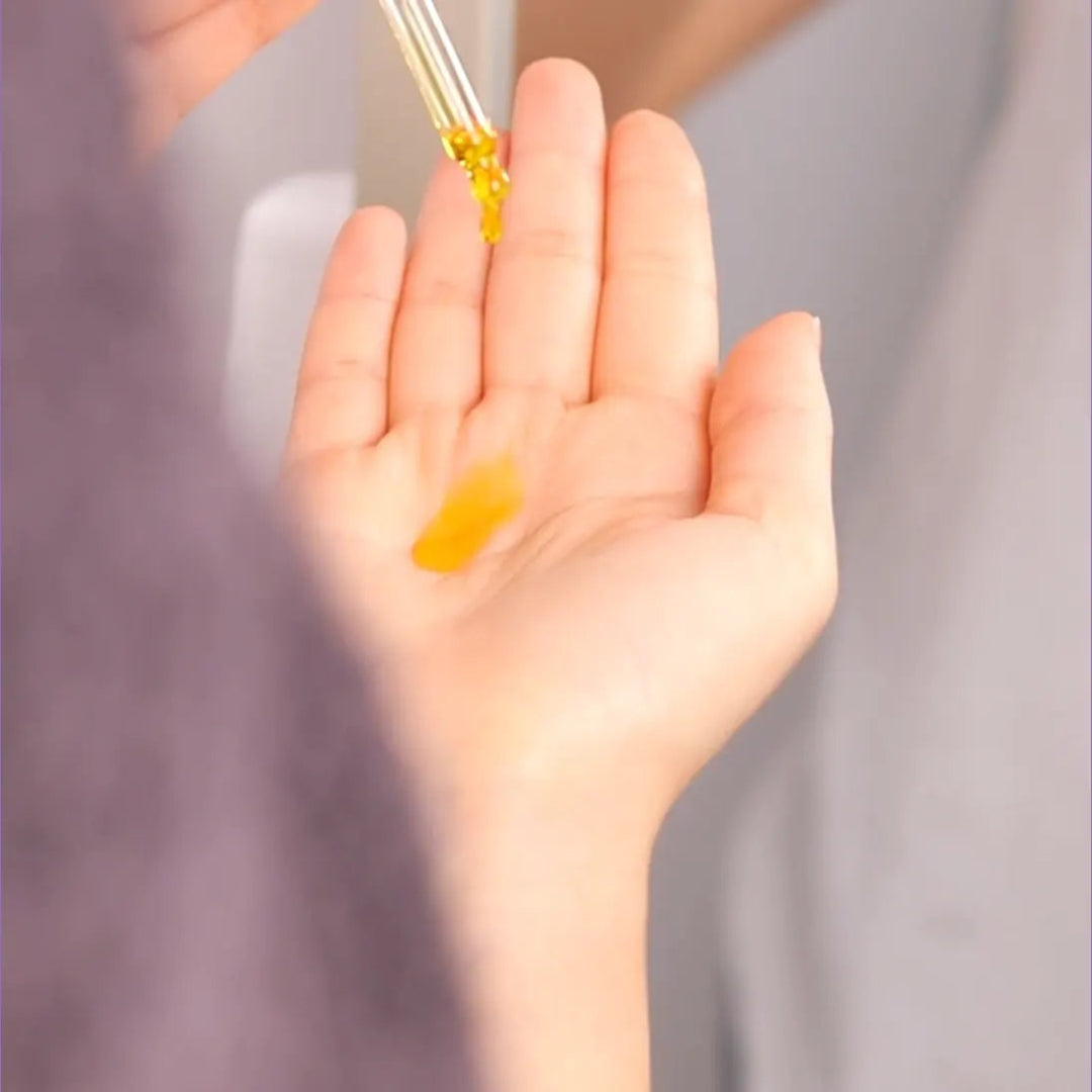 Dropper dripping serum on a hand