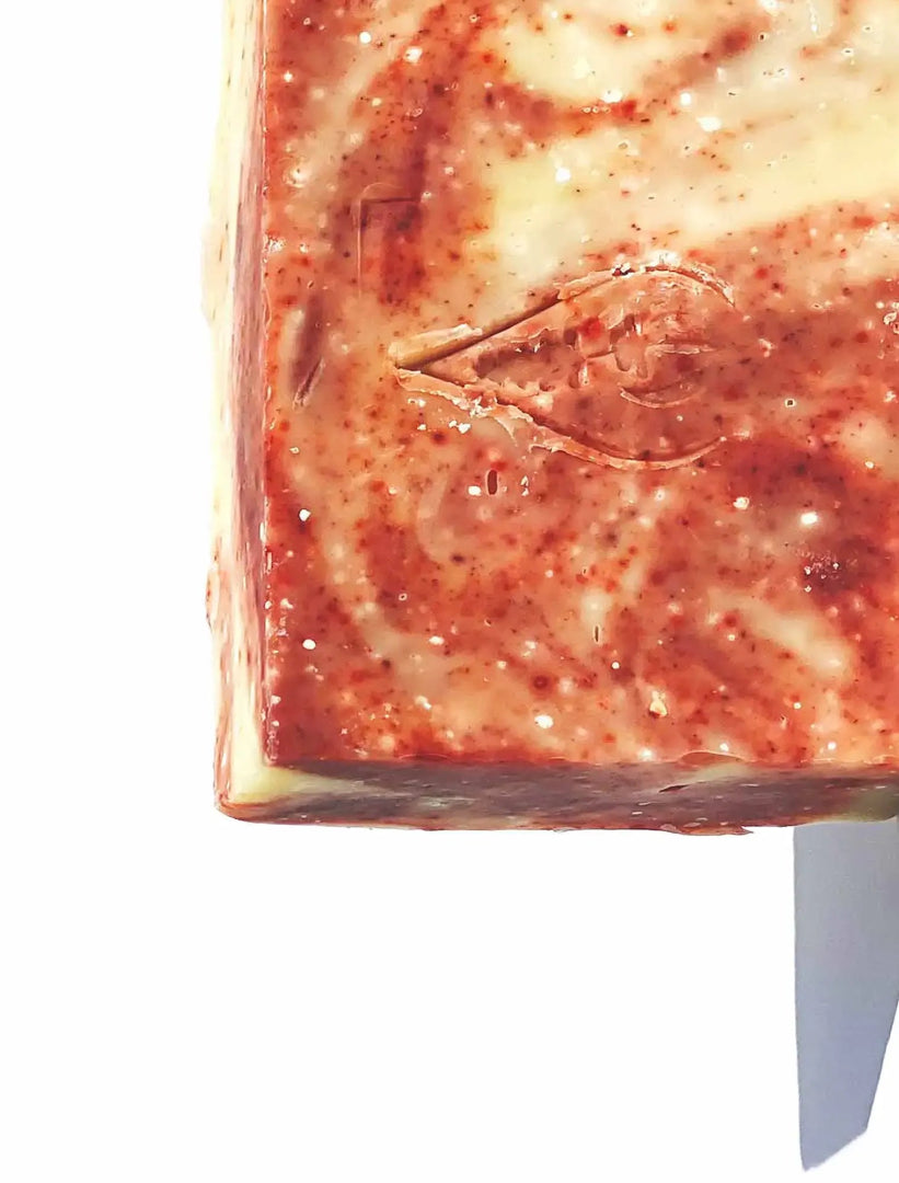 Close up of BY VALENTI Himalayan Pink Salt Bar Soap showing the natural red colors of the soap on a white background
