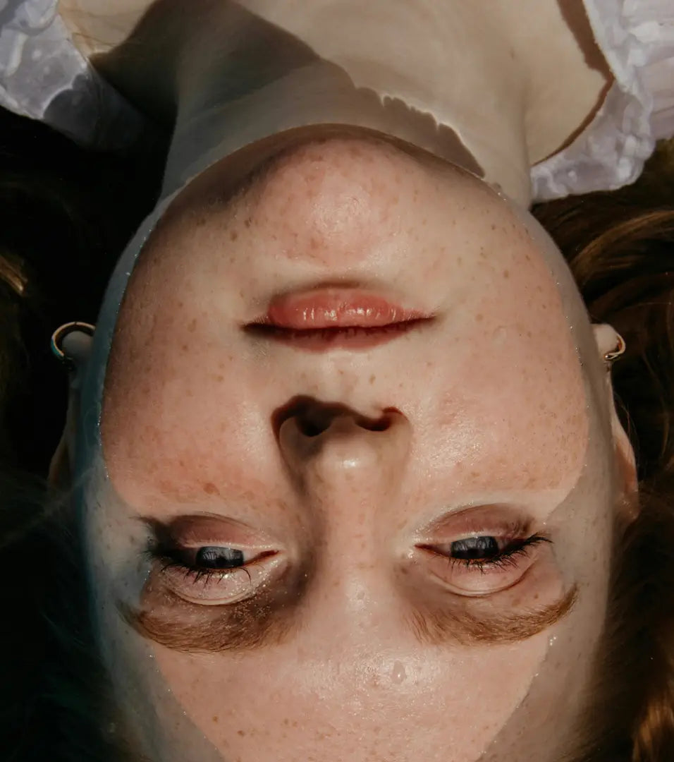 Close-up of a woman's face submerged in water.