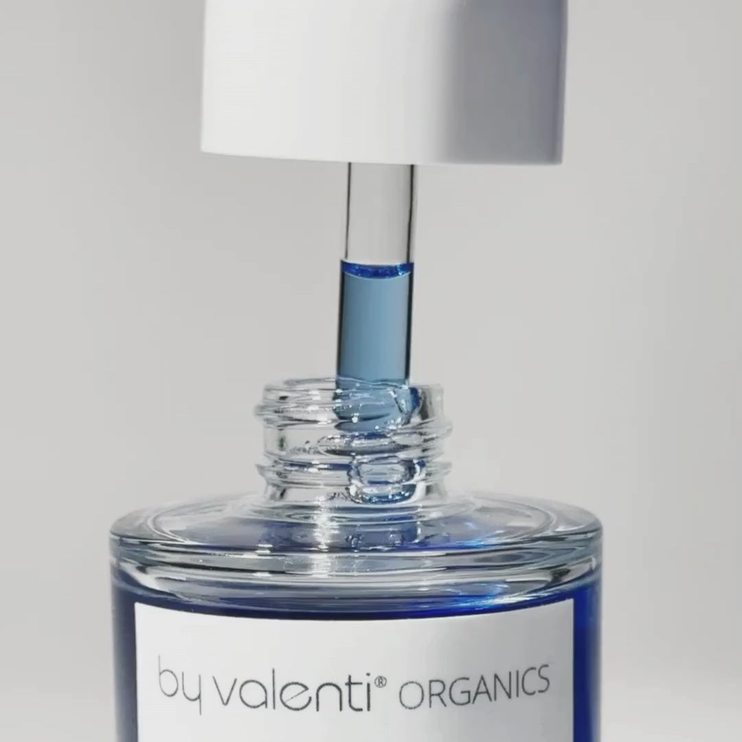 Bottle of By Valenti blue vitamin C serum and a dropped with the blue serum dripping serum back in the bottle